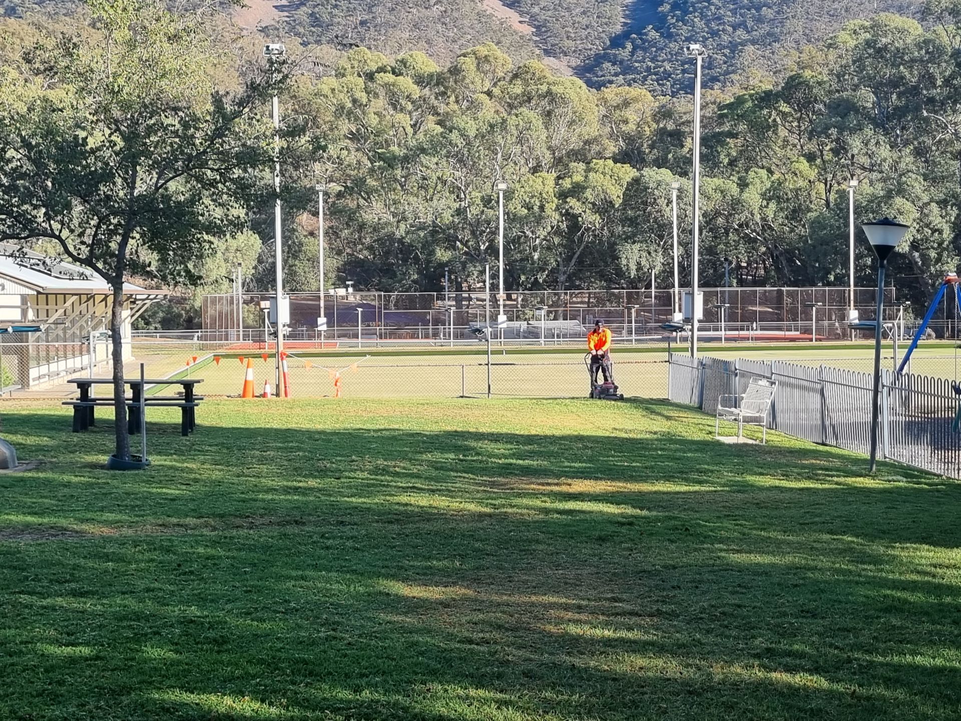 Worker mowing grass at a park in Melrose.