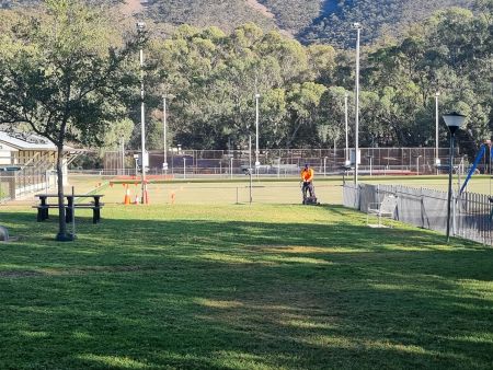 Worker mowing grass at a park in Melrose.