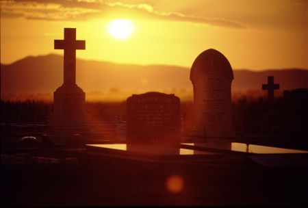 Sunset over mountain ranges behind headstones.