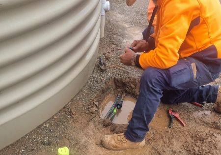 Worker fixing a water leak in underground poly pipe.