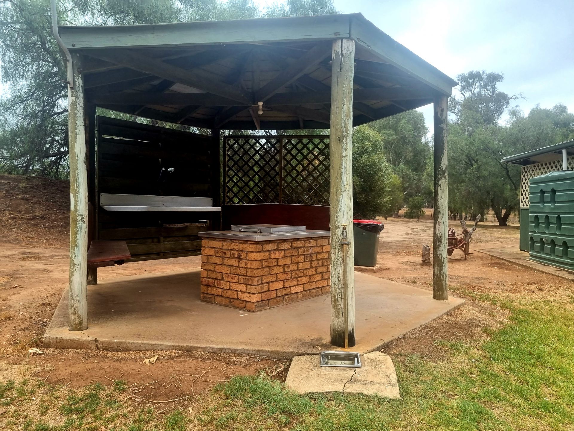 Seating and barbeque with brick sides under a pine post partially closed veranda.