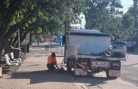Worker shown maintaining equipment next to parked truck.