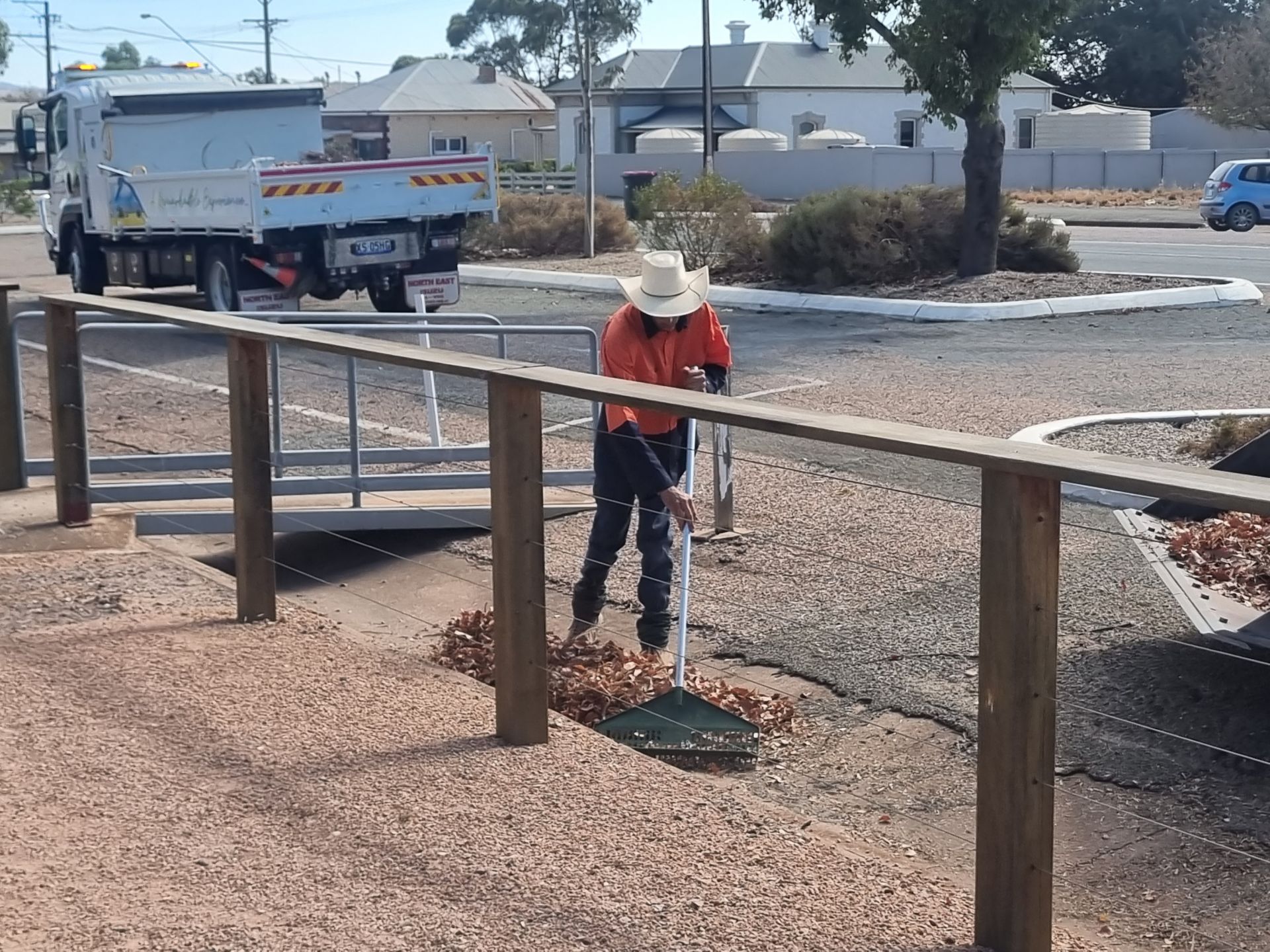 Council worker raking leaves out of a gutter.
