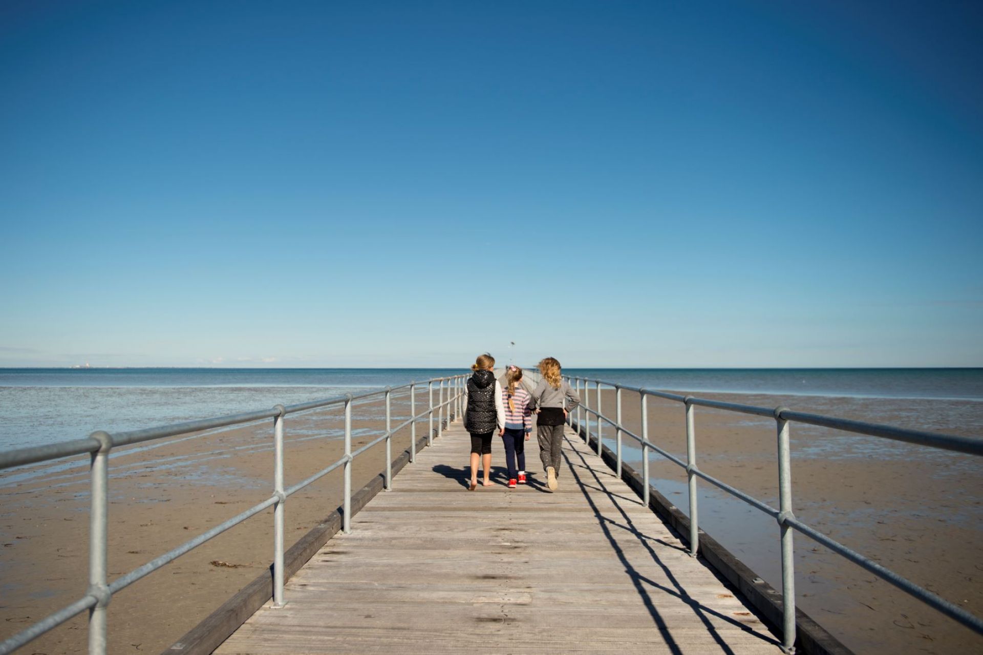 Three young children walking up Port Germein Jetty