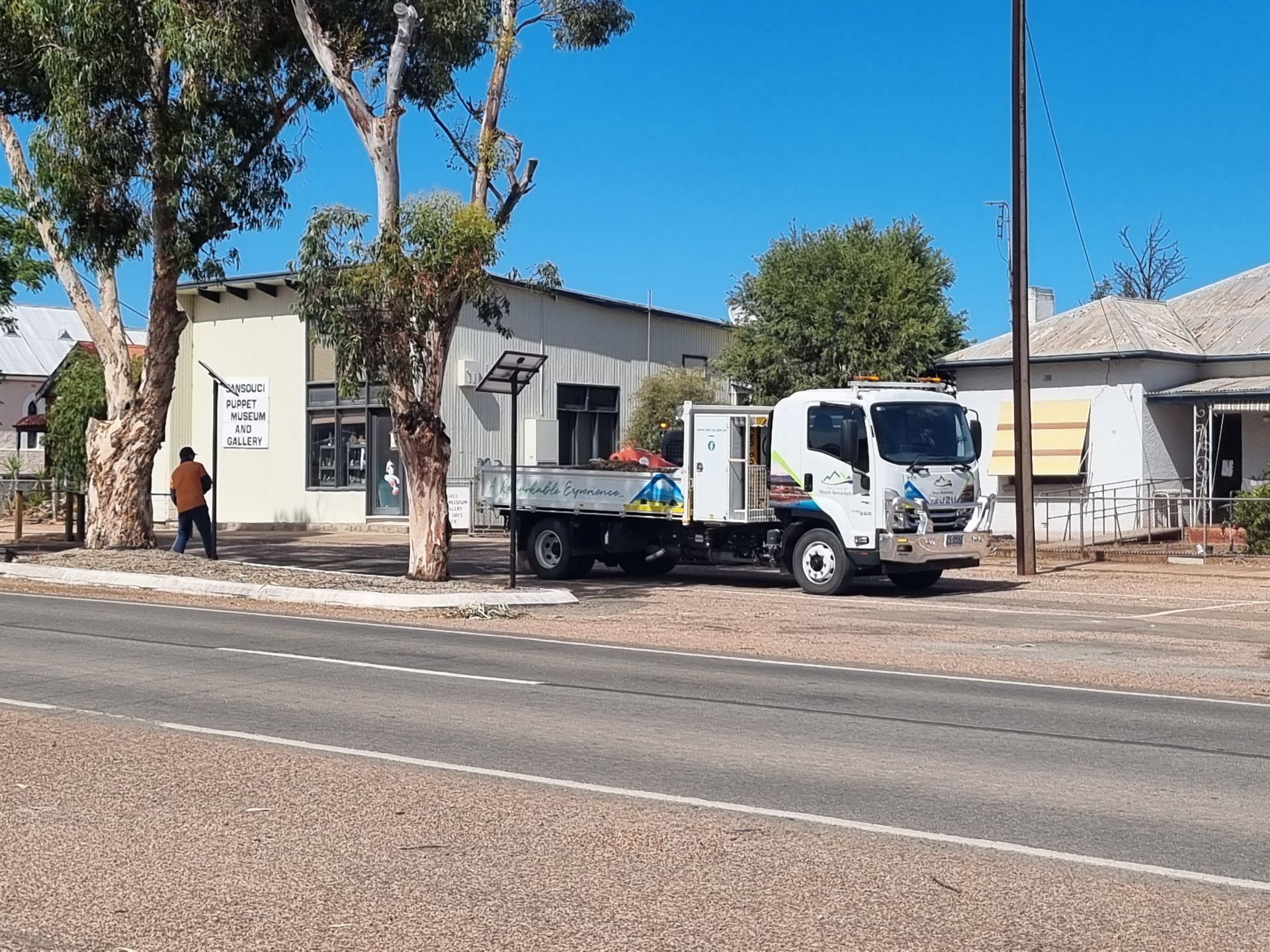 The council town truck parked on the side of a bitumen road with a worker in the background.
